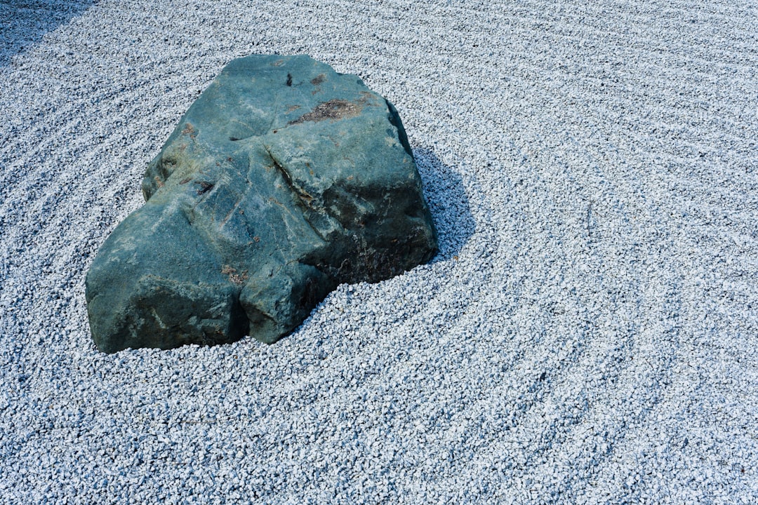 A Large Grey Rock Situated in a White Gravel Zen Garden - A single, large, grey rock sits on a bed o